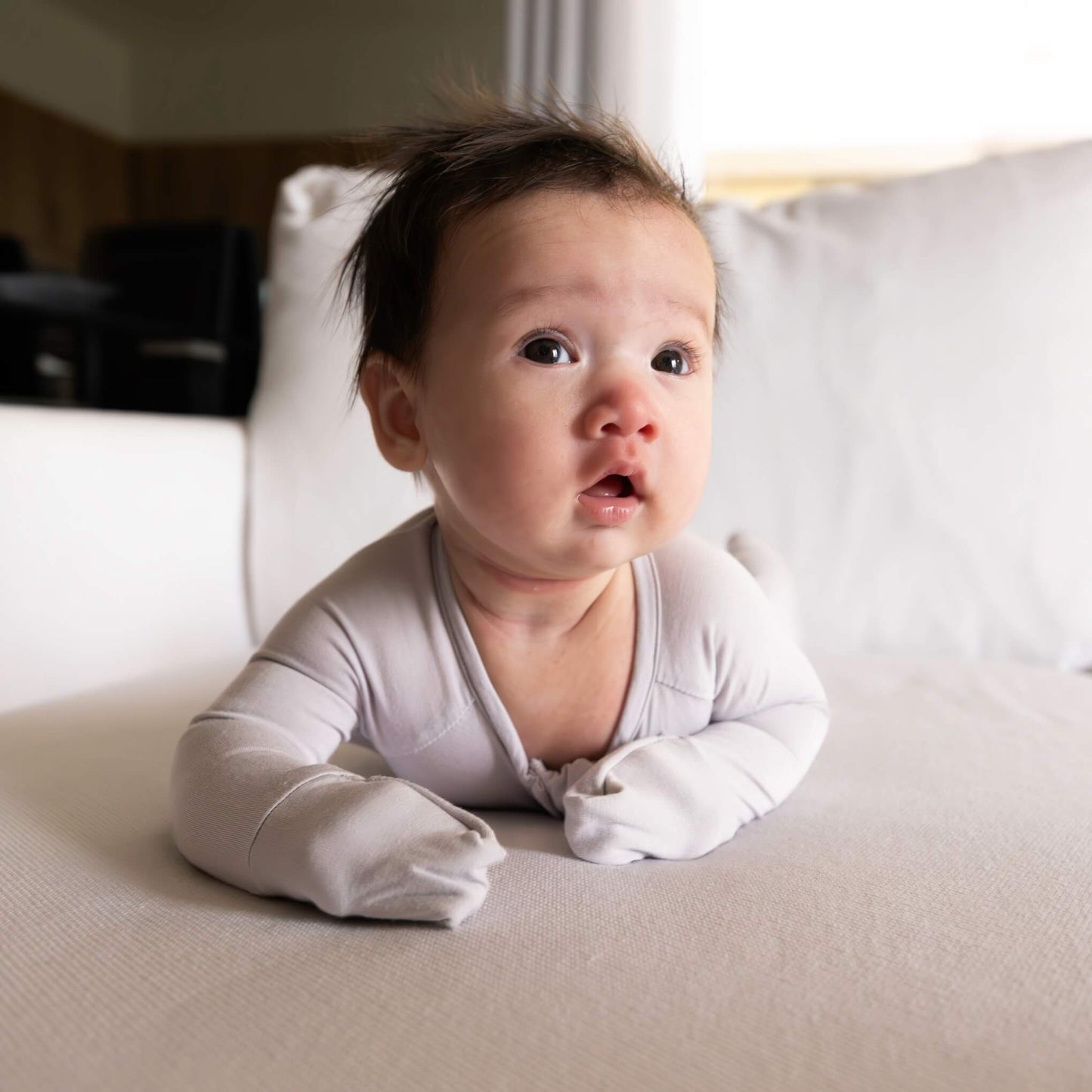 baby wearing grey pyjamas on tummy