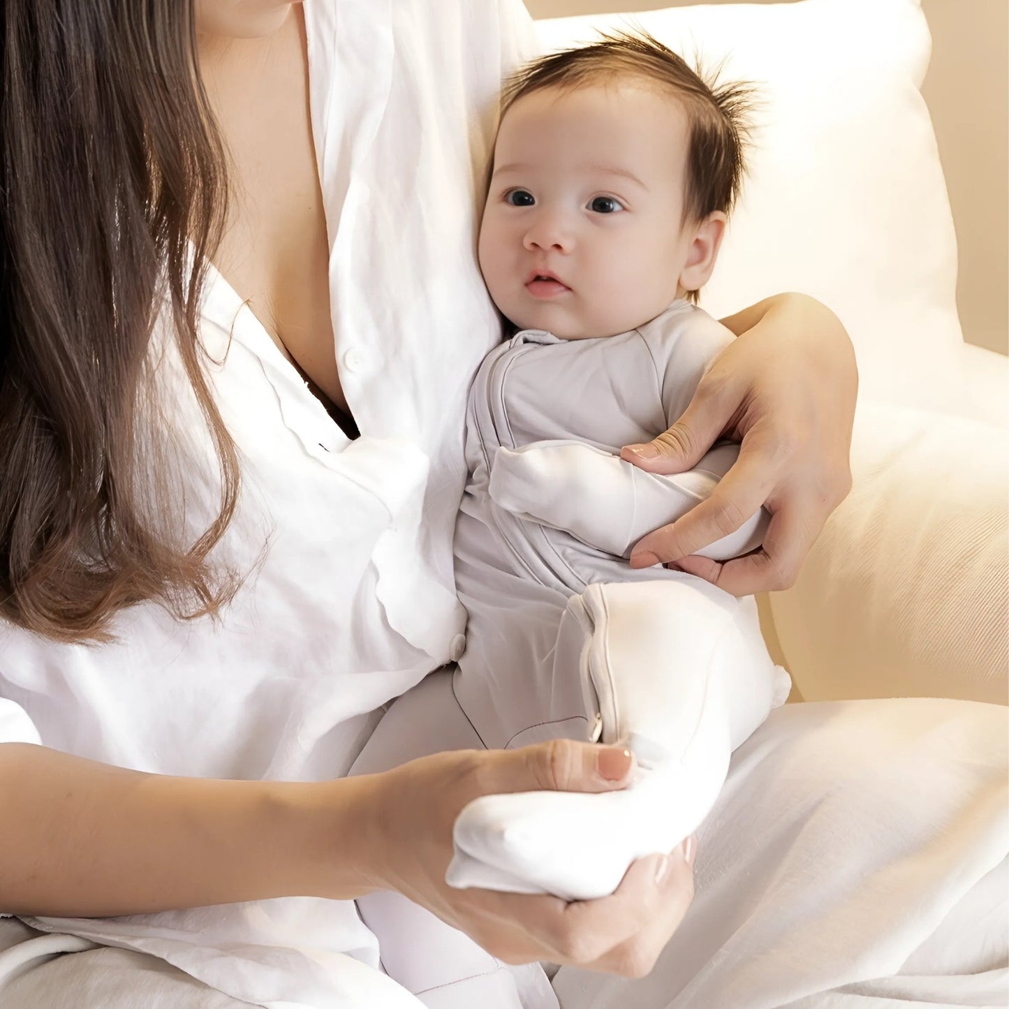 Baby wearing grey pyjamas sitting in mums arms