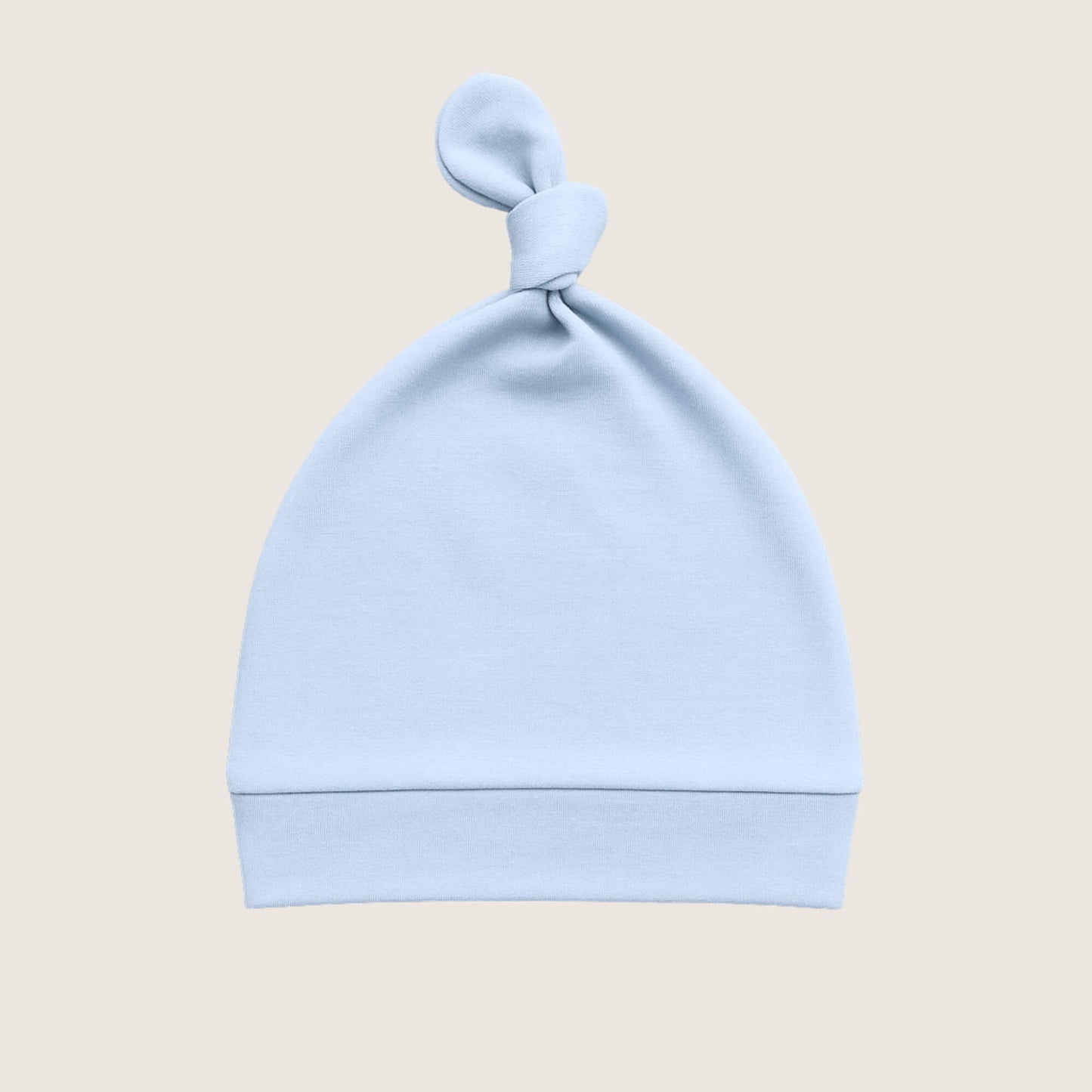 Light blue baby hat with a knot on top against a beige background