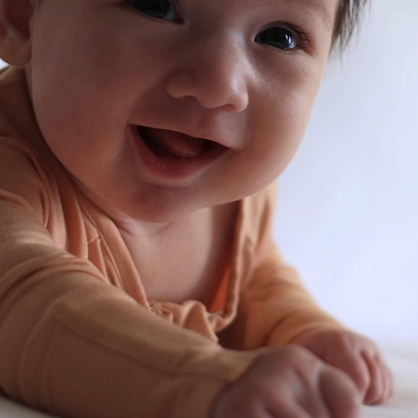 Baby in a peach onesie laying on tummy