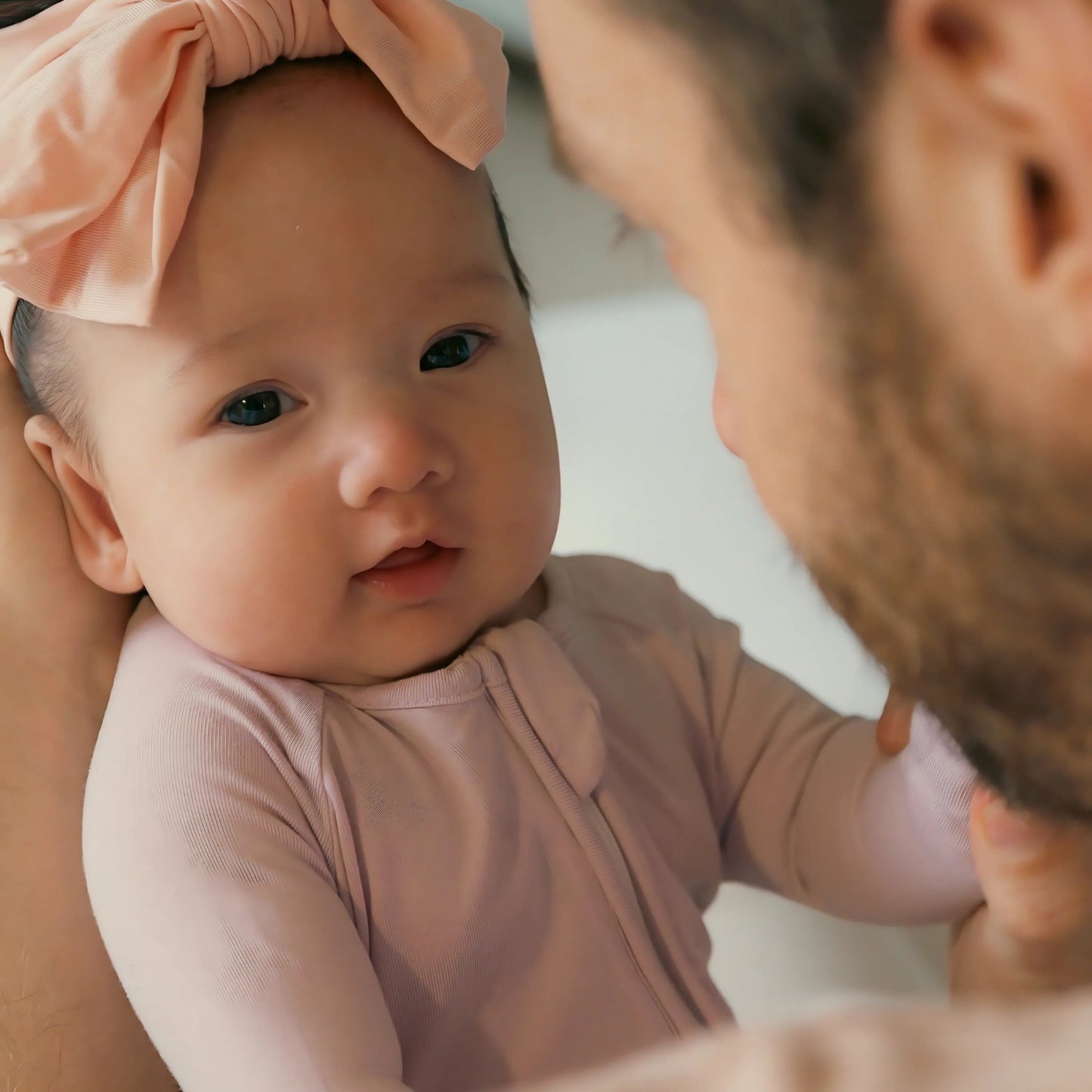 Baby wearing a lavender pyjamas being held by dad