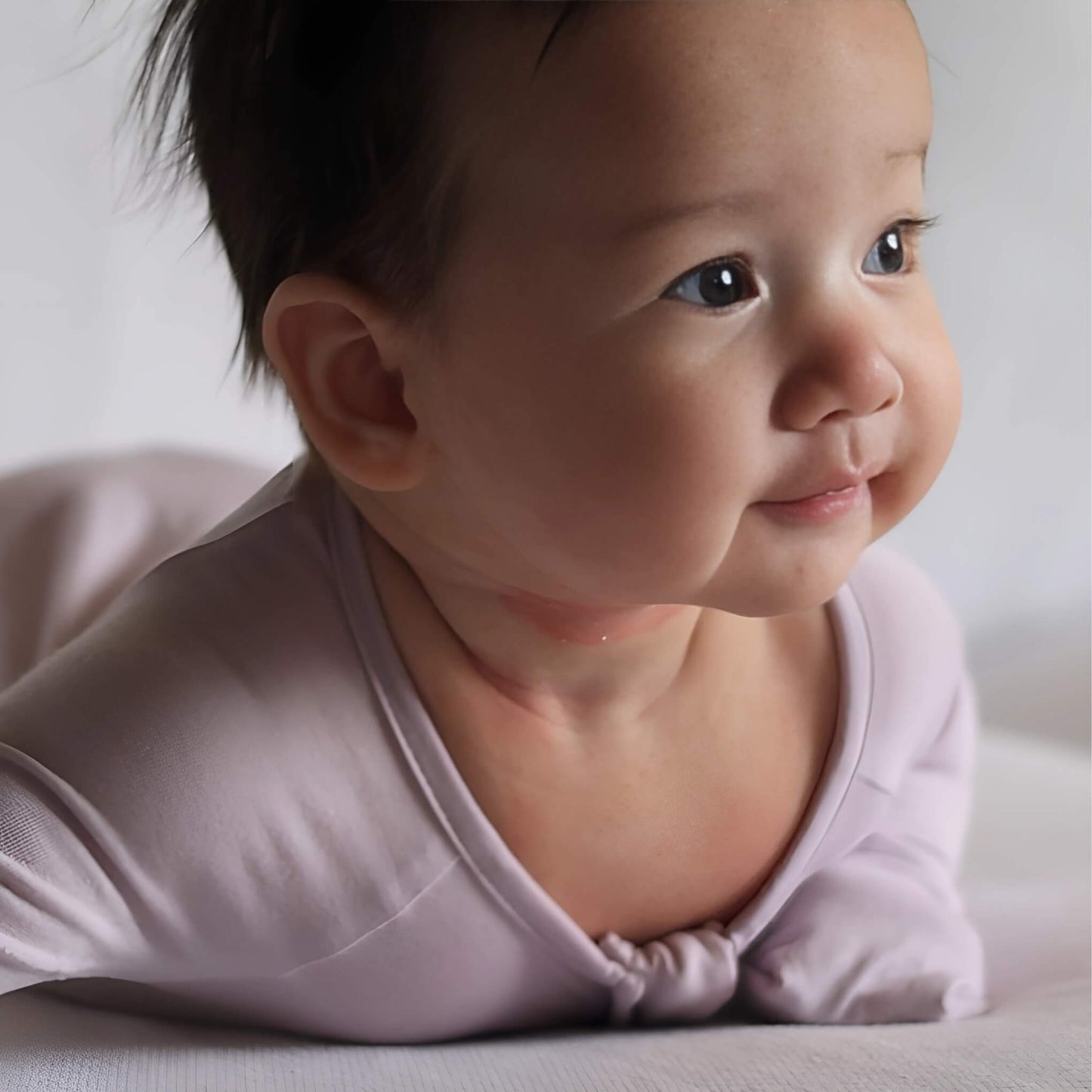 Baby wearing a lavender pyjamas on tummy