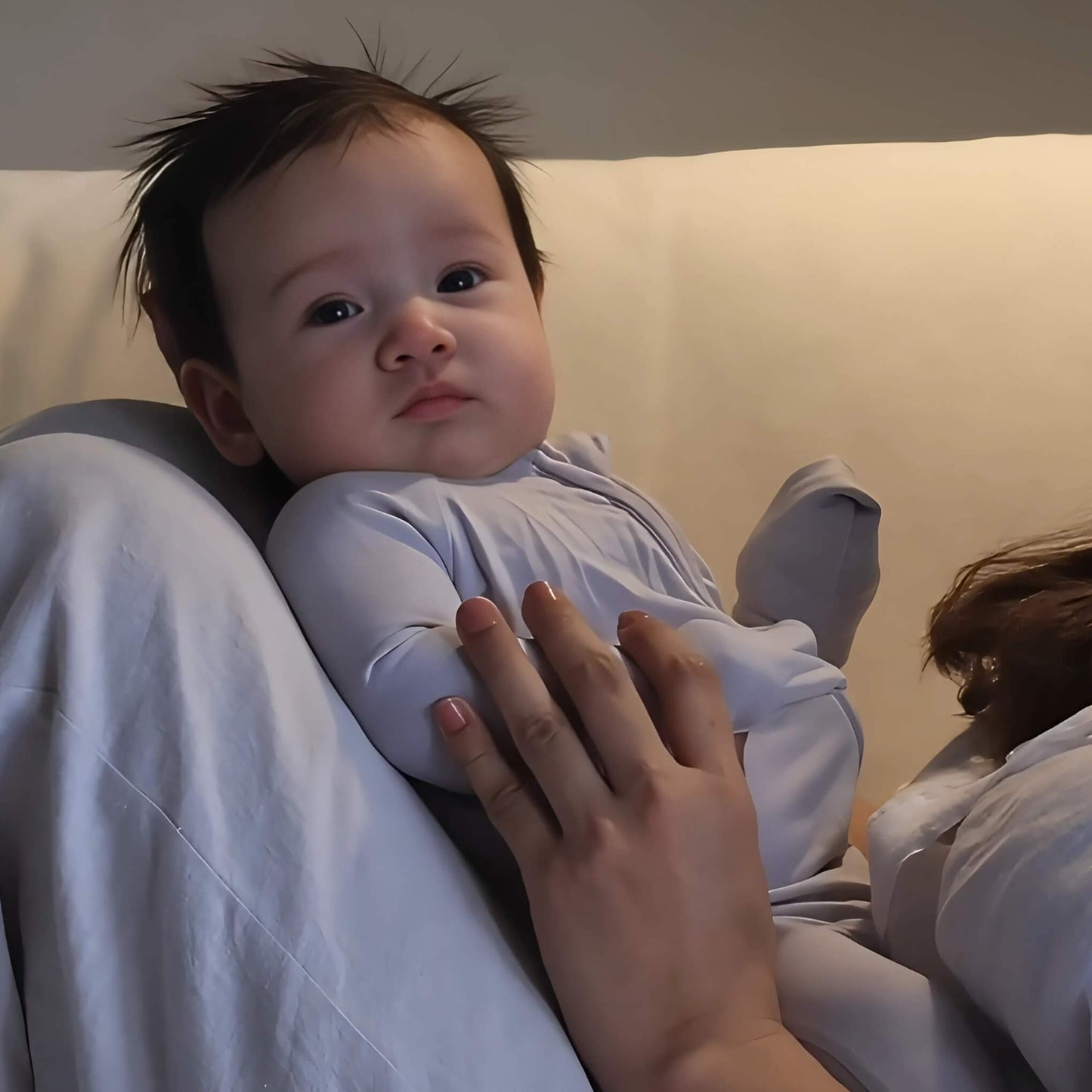 Baby wearing grey pyjamas laying in mums arms
