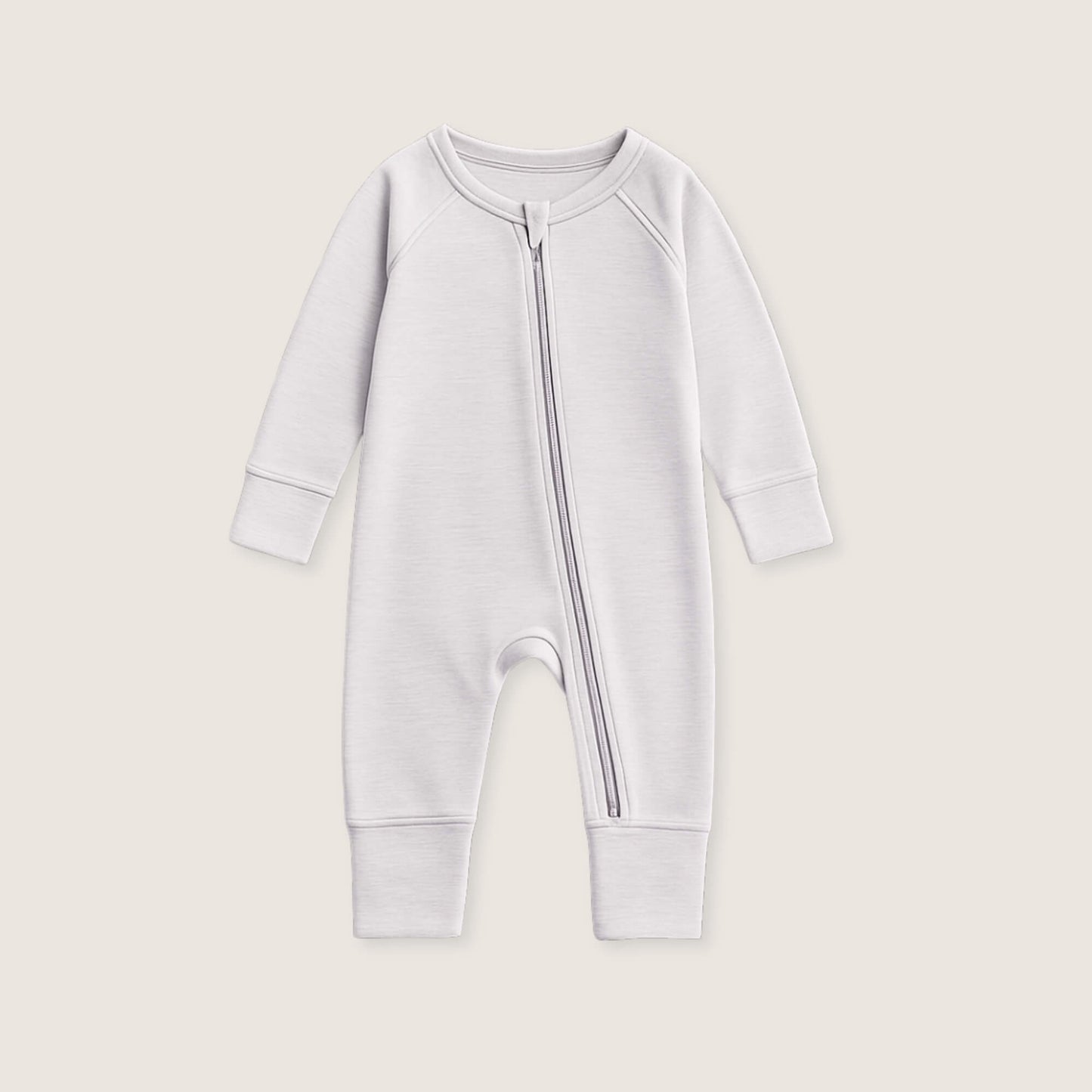 White baby onesie with a zipper on a beige background