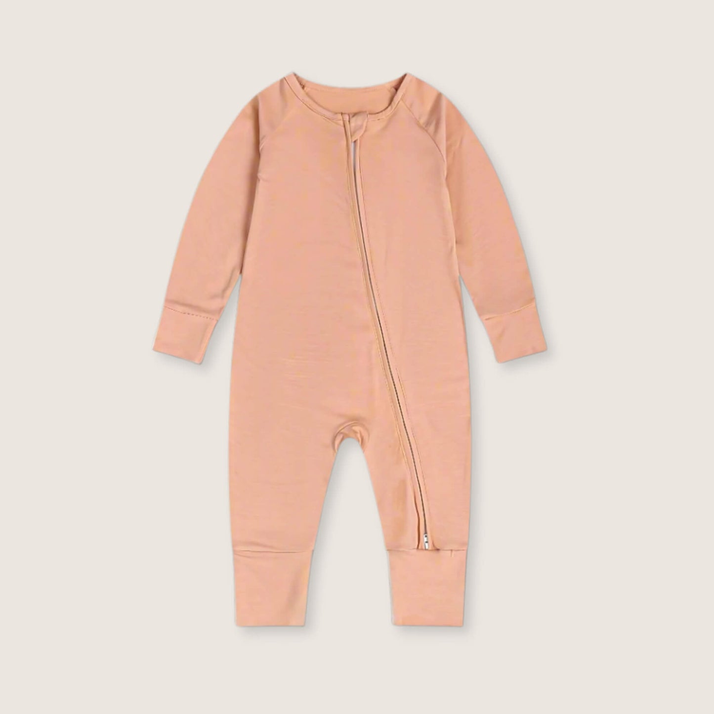 Peach baby onesie with a zipper on a light beige background