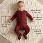 Baby wearing a maroon bamboo baby grow laying on white blanket