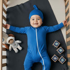 Baby wearing deep blue bamboo baby grow in crib