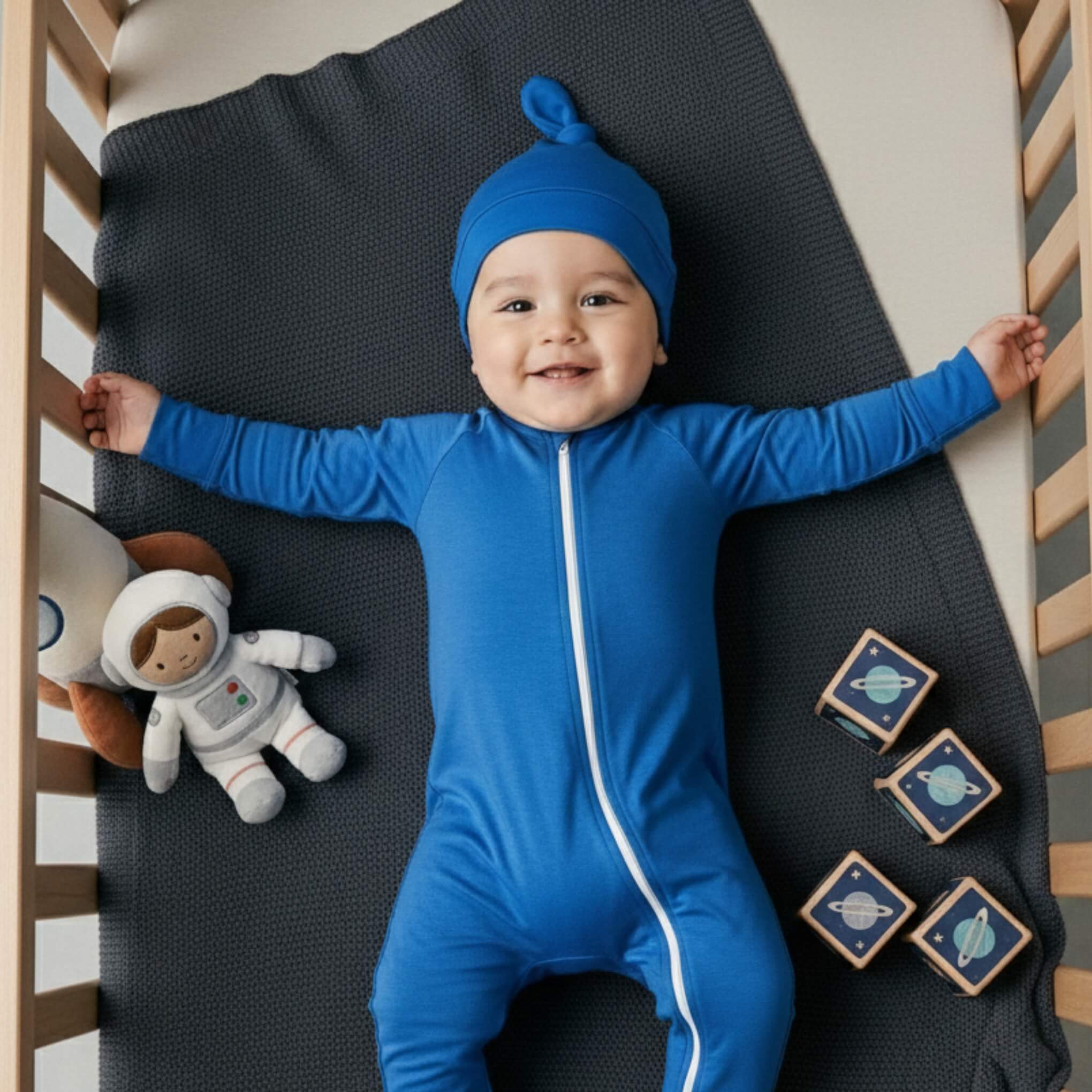 Baby wearing deep blue bamboo baby grow in crib