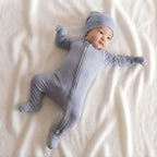 Baby in a dark blue bamboo baby grow laying on white blanket