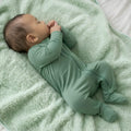 Sleeping Baby in green bamboo baby grow on green blanket