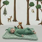 Baby in green baby grow lying on a knitted blanket