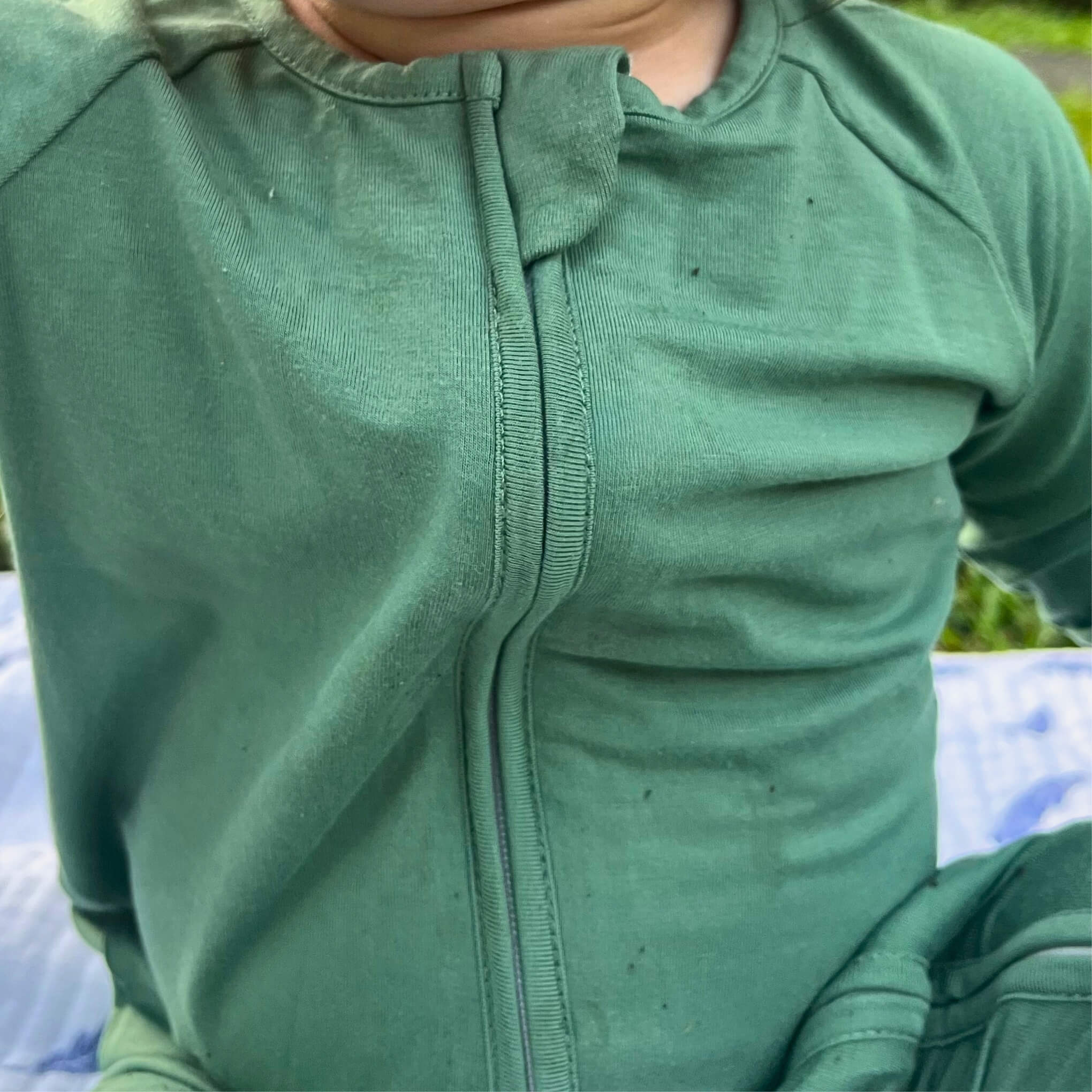 Green zip-up baby grow worn by a toddler 