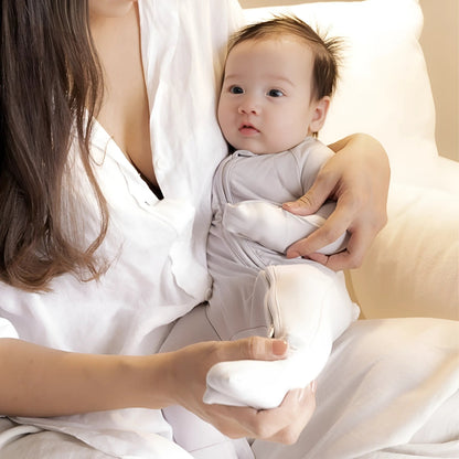 Baby wearing grey pyjamas sitting in mums arms 