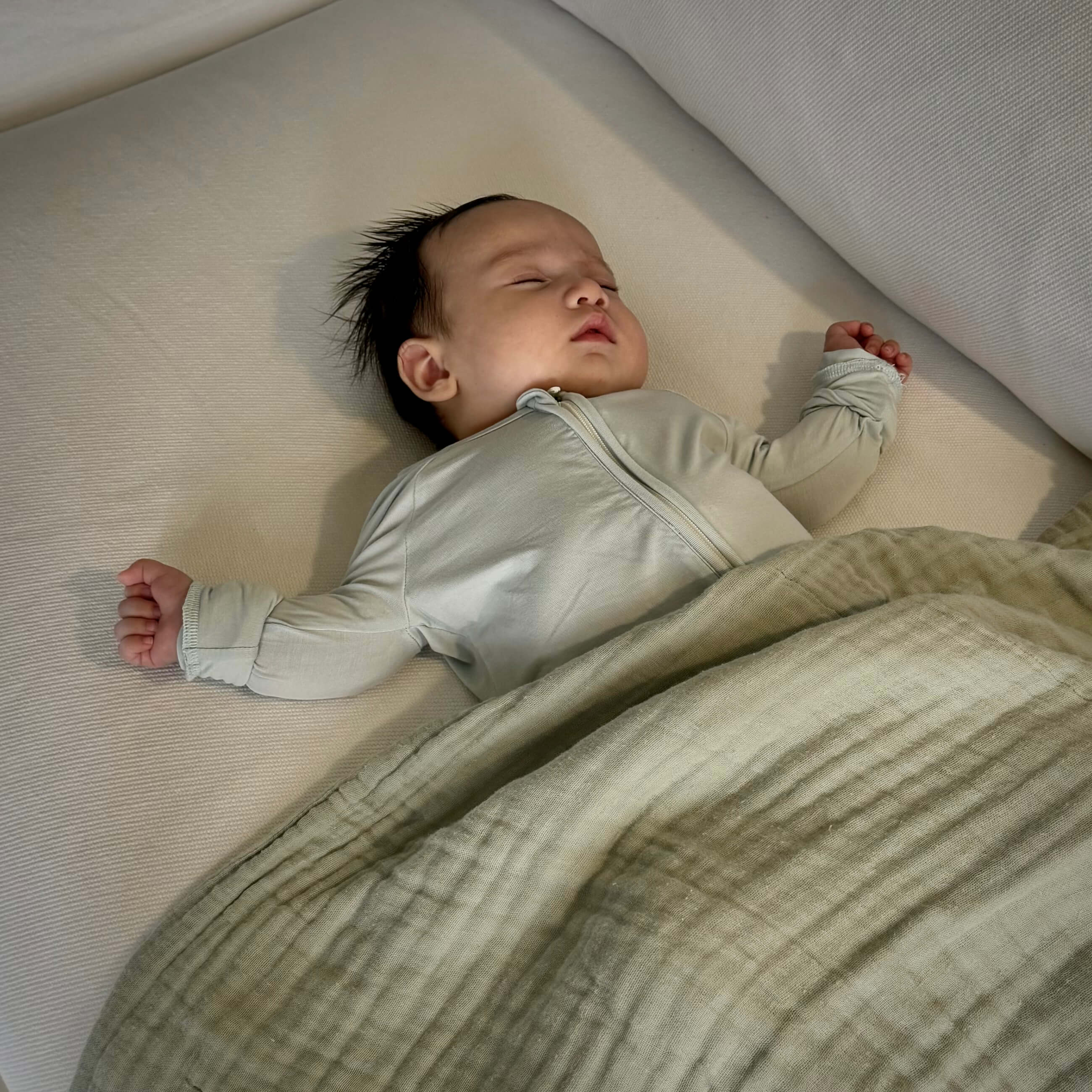 Baby sleeping on a mattress with a soft bamboo blanket