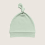 Mint green baby hat with a knot on top against a light beige background