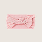 Pink headband with a large bow on a light pink background