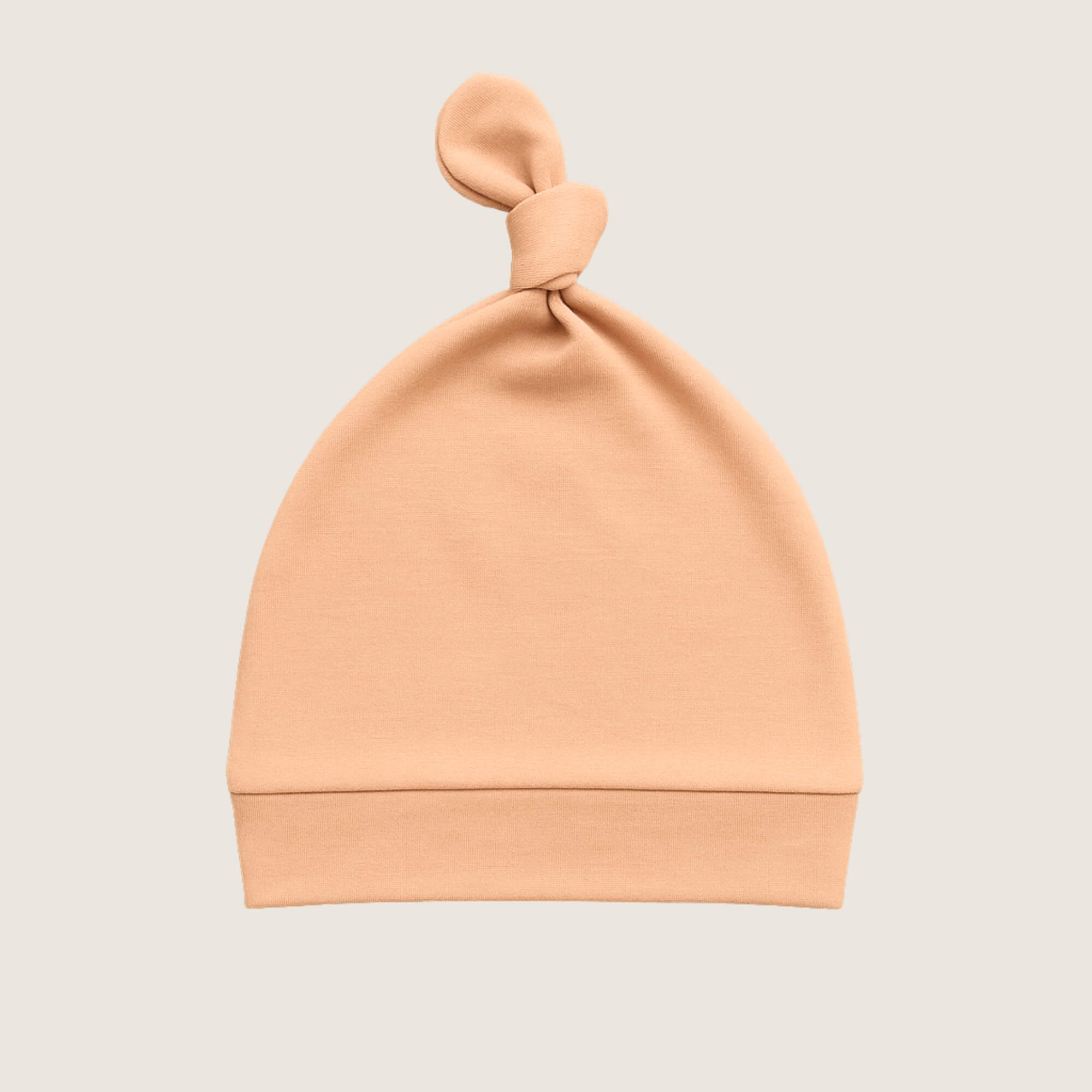 Orange baby hat with a knot on a light grey background
