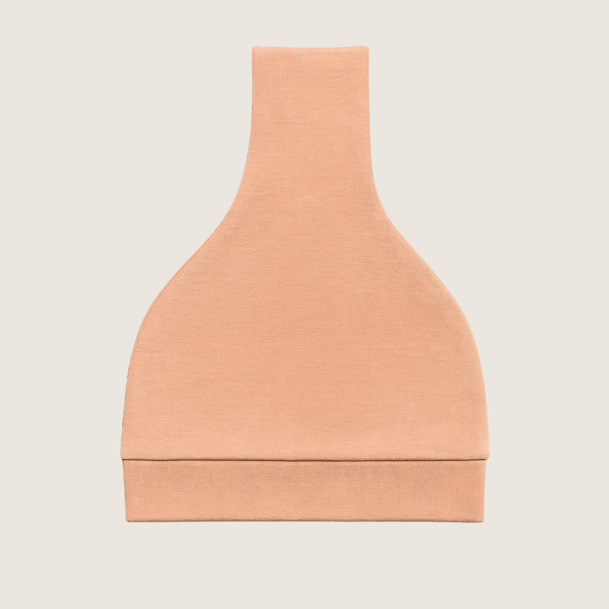 Orange baby hat folded with a knot on a light grey background