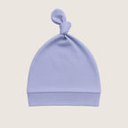 Light blue baby hat with a knot on top against a beige background