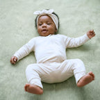 Newborn in light brown bamboo baby grow and bow