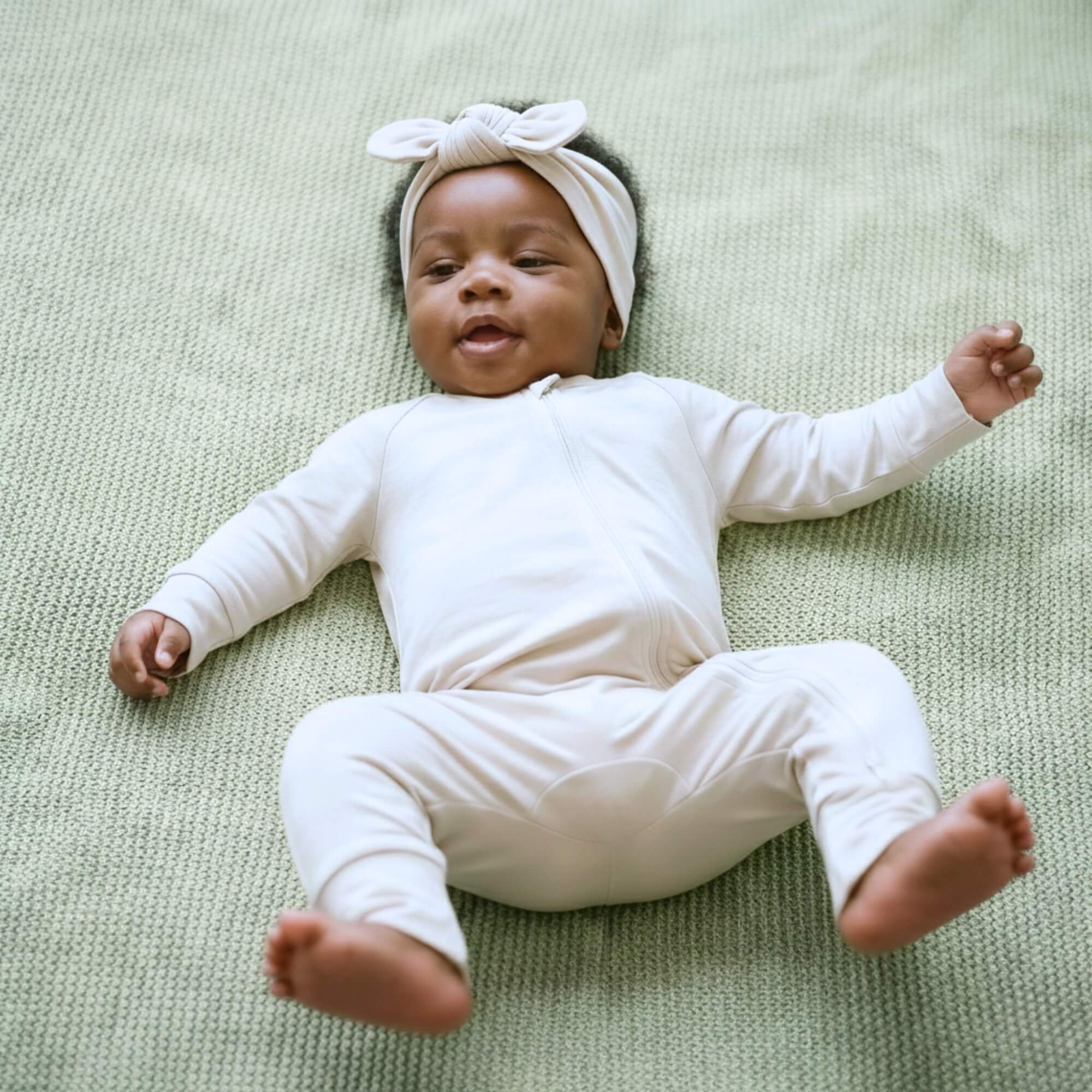 Newborn in light brown bamboo baby grow and bow