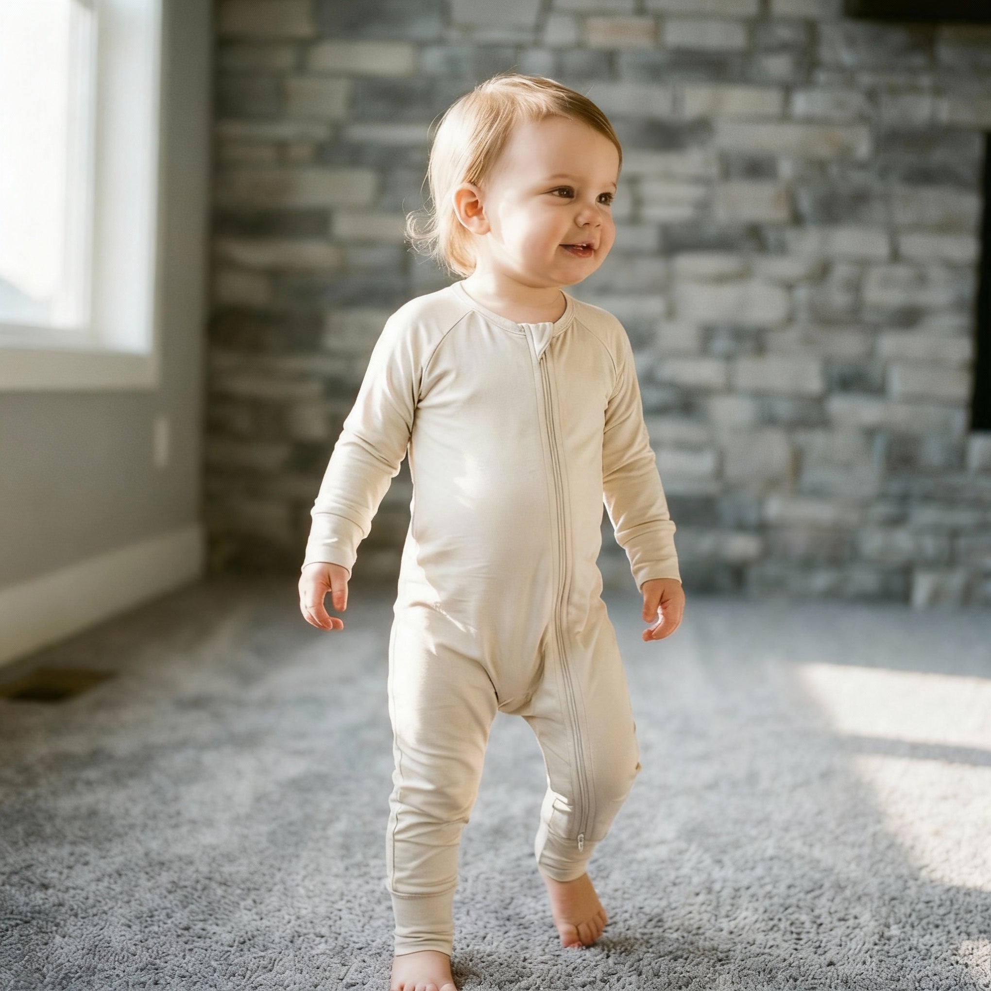 Toddler standing wearing a light brown bamboo baby grow
