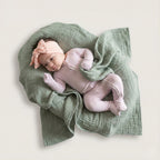 Baby girl wearing a lavender pyjamas laying on green blanket