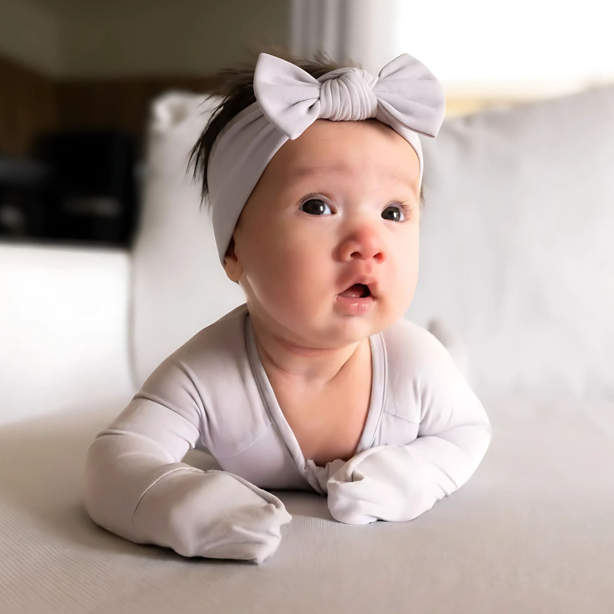Baby wearing a light grey pyjamas laying on tummy