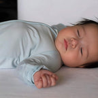 Baby wearing a light blue pyjamas sleeping on sofa