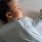 Baby wearing a light blue pyjamas laying on back