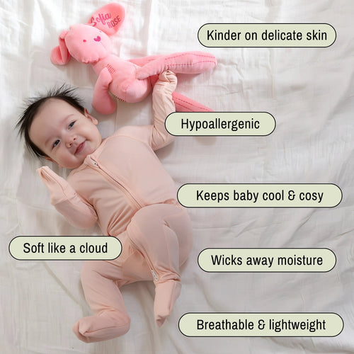 Baby wearing a pink bamboo pyjamas laying on white blanket