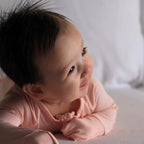 Baby wearing a pink bamboo pyjamas on tummy