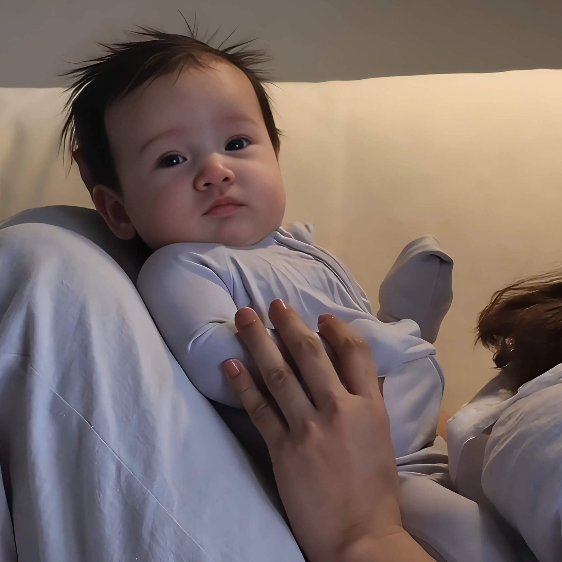 Baby wearing grey pyjamas laying in mums arms 