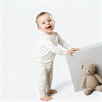 toddler standing wearing off white babygrow