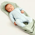 newborn baby boy wearing blue baby grow laying down