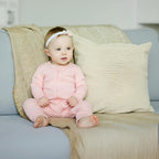 Baby wearing pink pyjamas on sofa