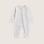 White baby onesie with a zipper on a beige background