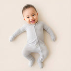 Baby wearing a gray onesie on a light beige background