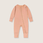Peach baby onesie with a zipper on a light beige background