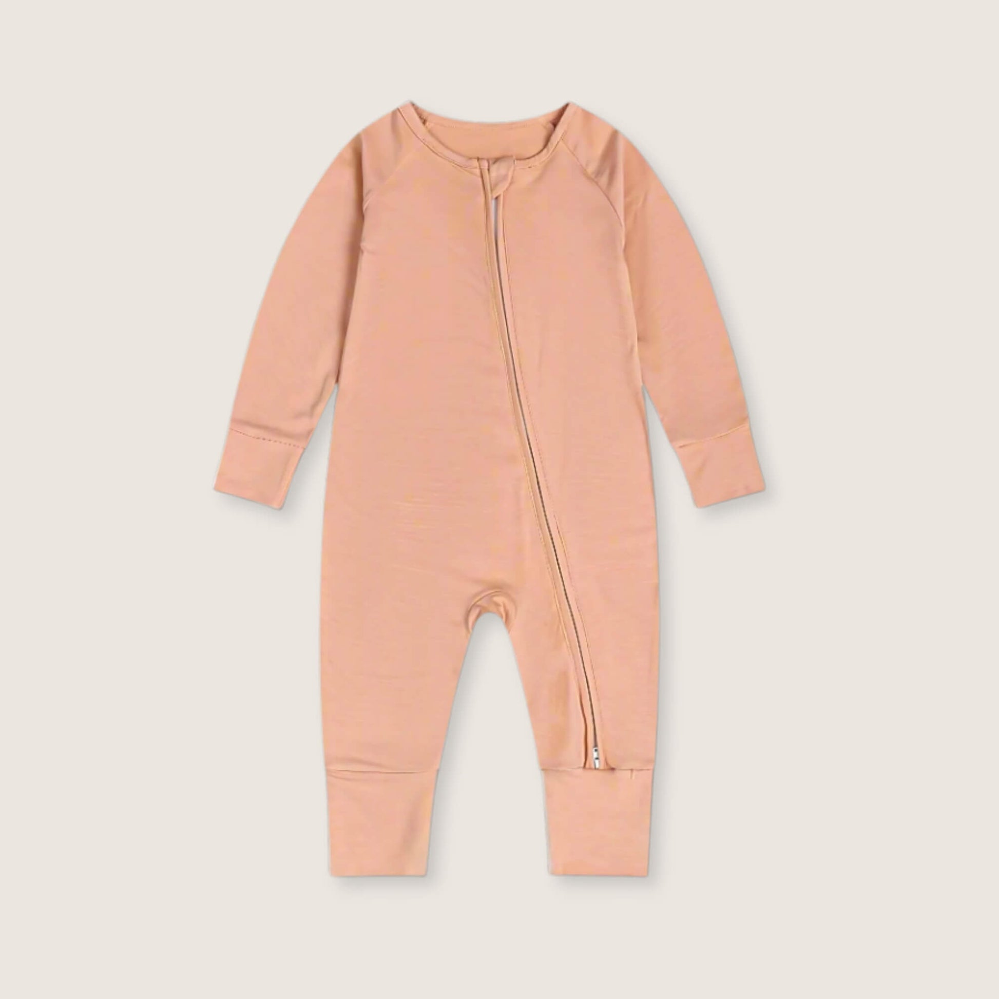 Peach baby onesie with a zipper on a light beige background