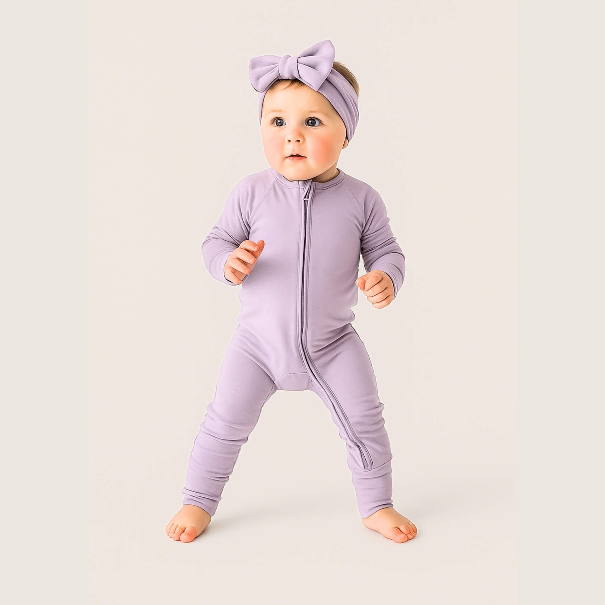 Baby wearing a purple onesie and headband on a light background