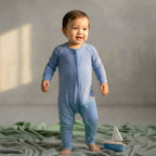 Boy wearing a blue bamboo baby grow in studio