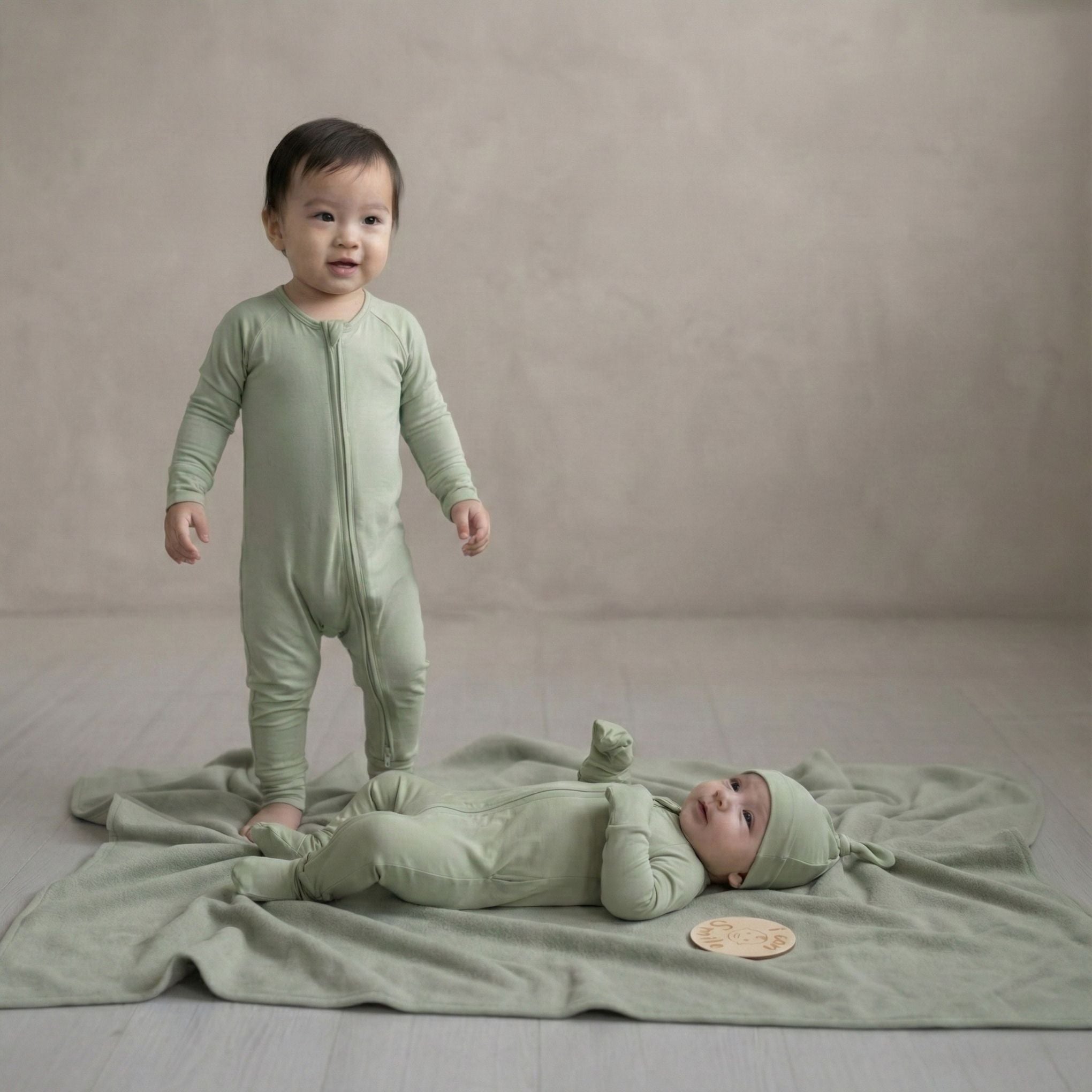toddler and baby girl wearing green baby grows in studio