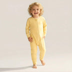 Toddler wearing yellow baby grow standing