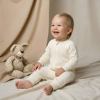 baby sitting wearing off white babygrow