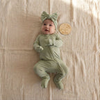 Baby wearing a green outfit and headband with a bow