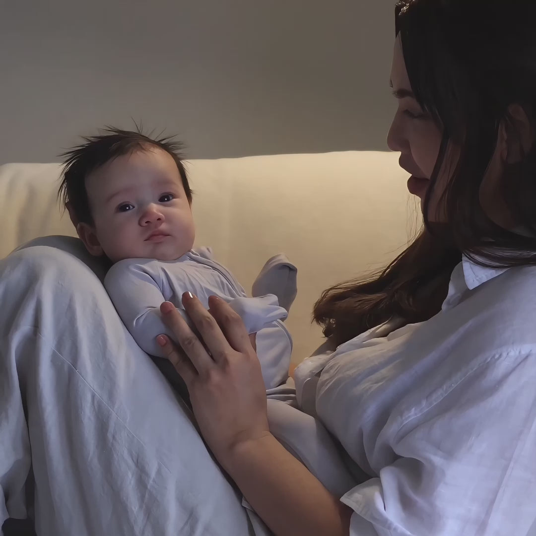 Baby wearing grey pyjama playing with mum