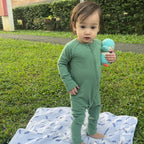 Baby girl playing park with green bamboo baby grow on