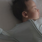 Baby wearing a light blue pyjamas sleeping on sofa