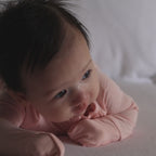 Baby wearing pink pyjama tummy time